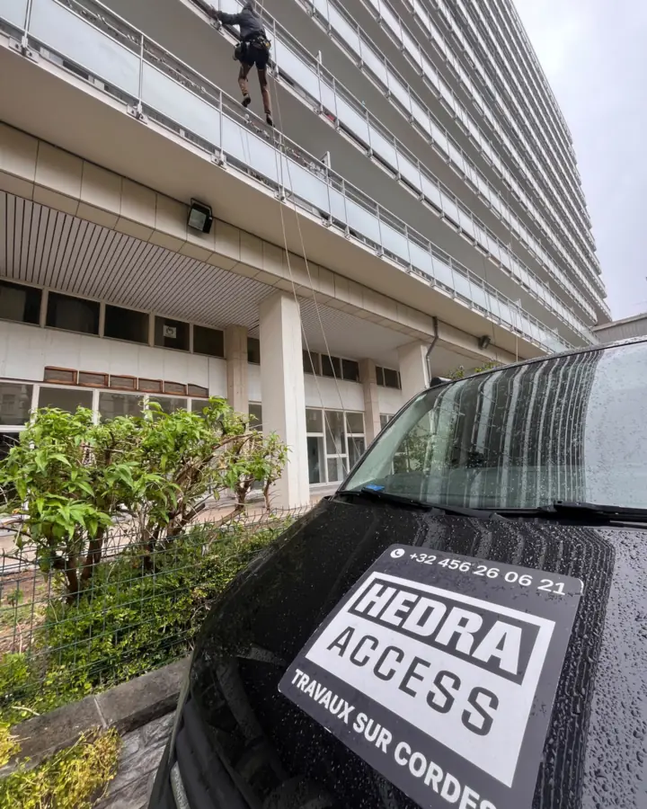 Camionnette Hedra Access garée au pied d'un immeuble, un cordiste en intervention sur la façade