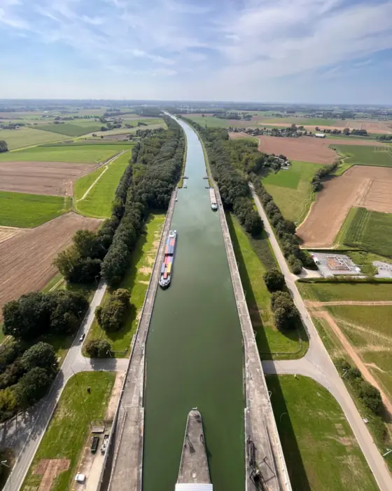 Un canal rectiligne et une péniche chargée de conteneurs, vus de très haut